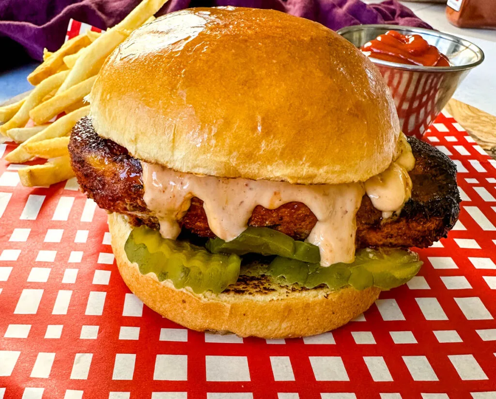 blackened chicken sandwich on a bun with spicy mayo on a plate with fries