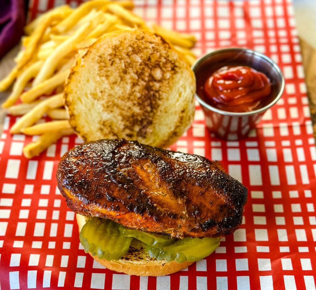 blackened chicken sandwich on a bun on a plate with fries