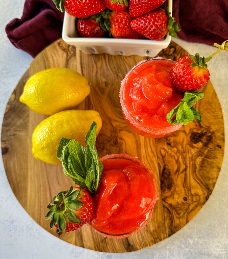 frozen strawberry lemonade in glasses garnished with fresh strawberries and fresh lemons