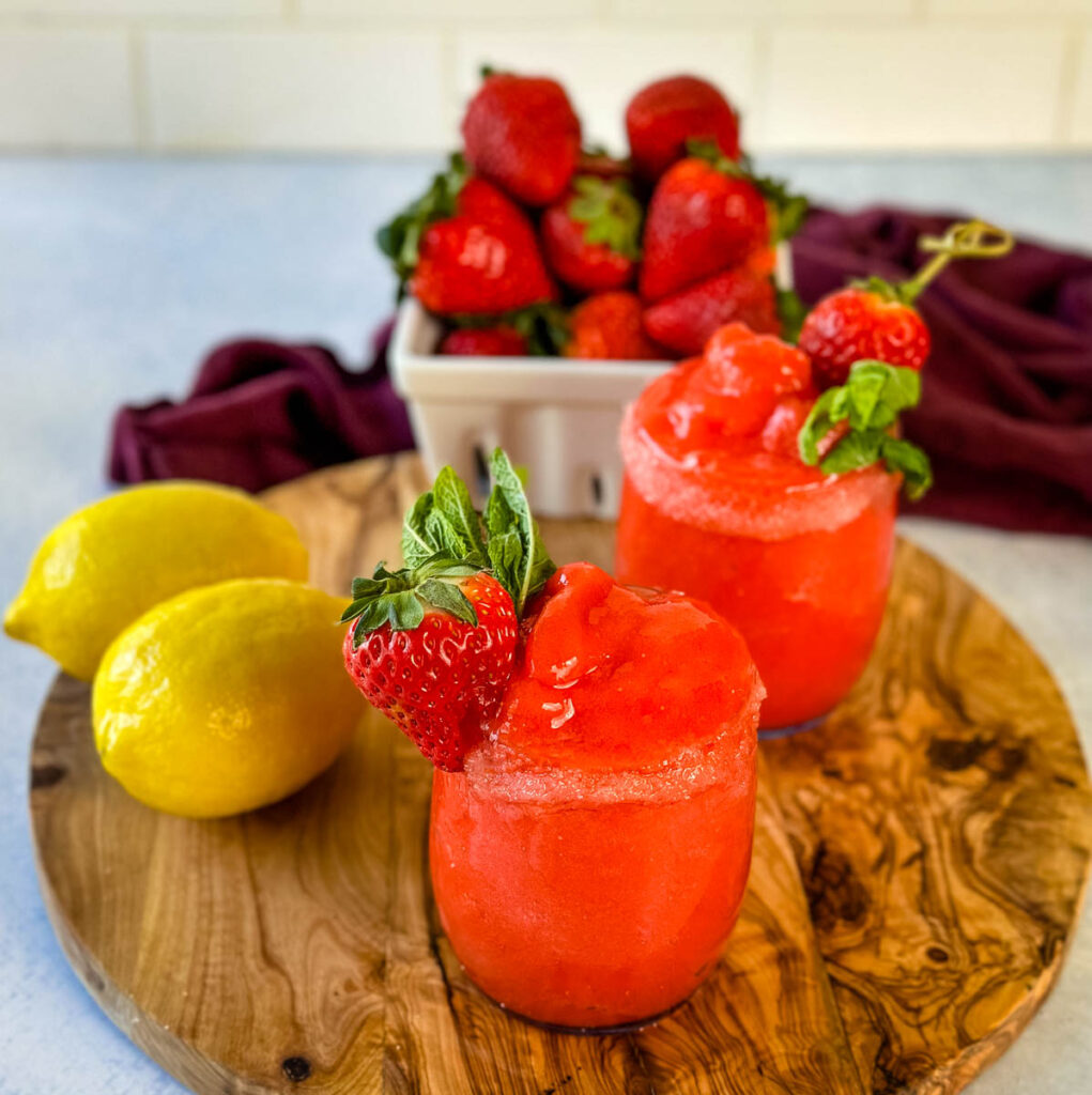 frozen strawberry lemonade in glasses garnished with fresh strawberries and fresh lemons