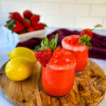 frozen strawberry lemonade in glasses garnished with fresh strawberries and fresh lemons