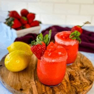 frozen strawberry lemonade in glasses garnished with fresh strawberries and fresh lemons