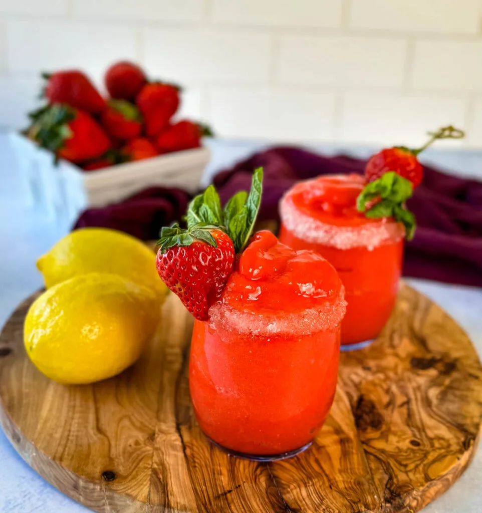 frozen strawberry lemonade in glasses garnished with fresh strawberries and fresh lemons