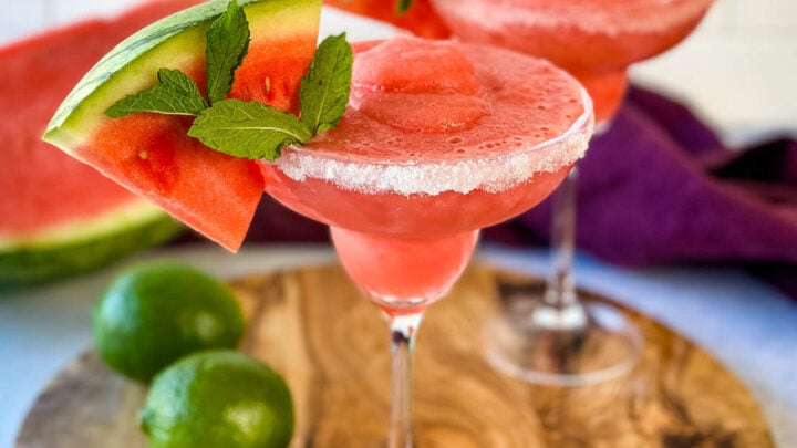 frozen margaritas in a sugar rimmed lined glass with fresh watermelon and limes