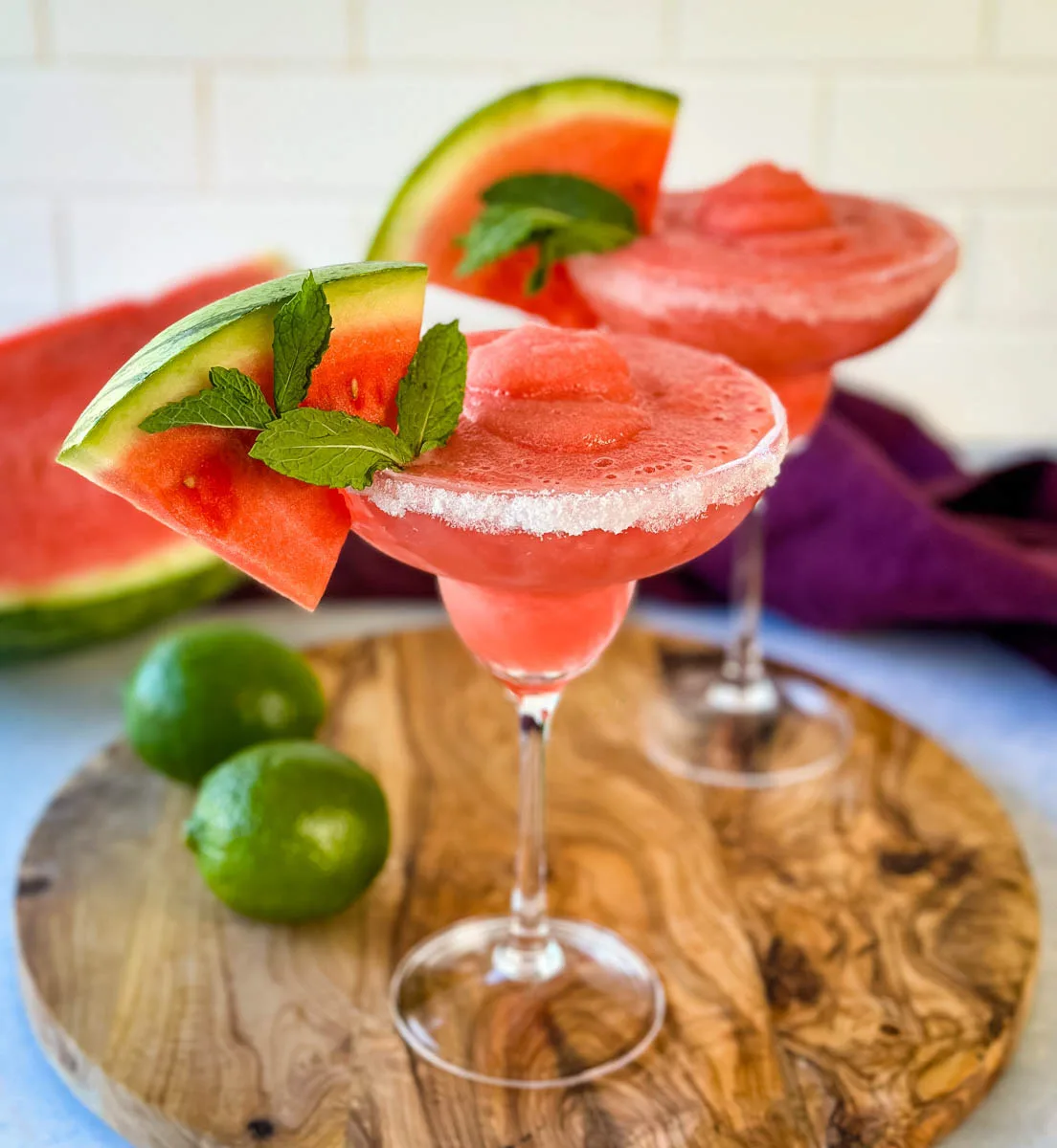 frozen margaritas in a sugar rimmed lined glass with fresh watermelon and limes