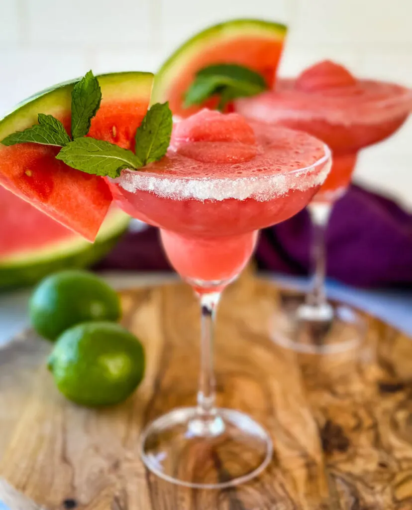 frozen margaritas in a sugar rimmed lined glass with fresh watermelon and limes