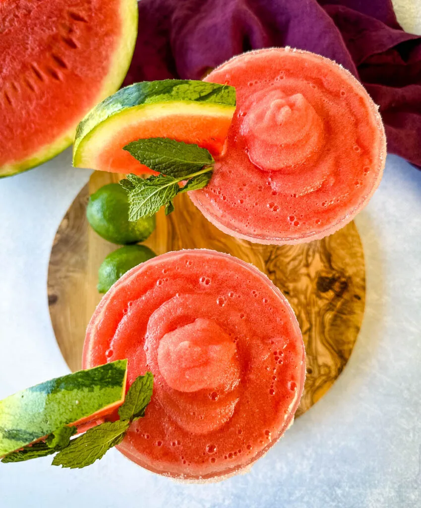 frozen margaritas in a sugar rimmed lined glass with fresh watermelon and limes