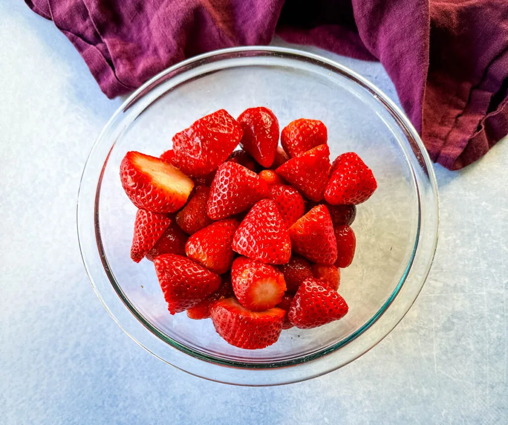 fresh cut strawberries in a glass bowl