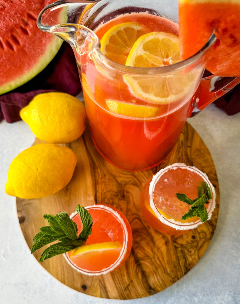 watermelon lemonade in glasses and a pitcher with fresh watermelon and lemons