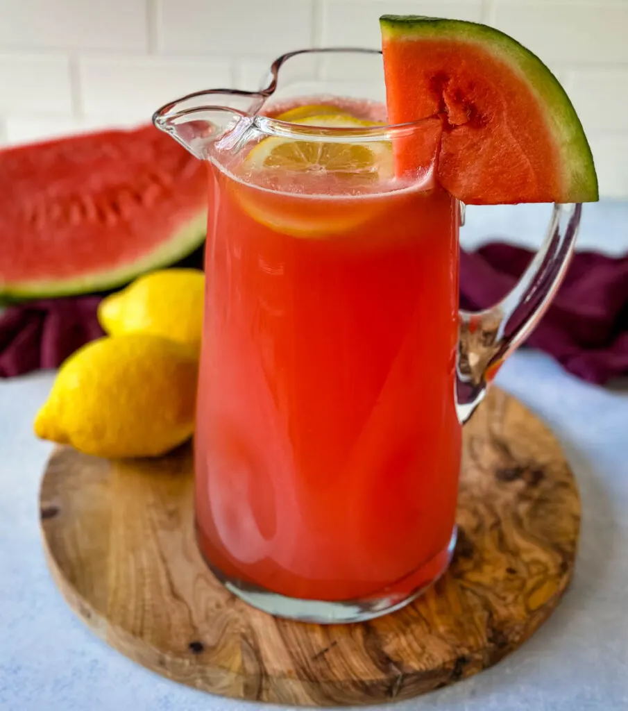 watermelon lemonade in a pitcher with fresh watermelon and lemons