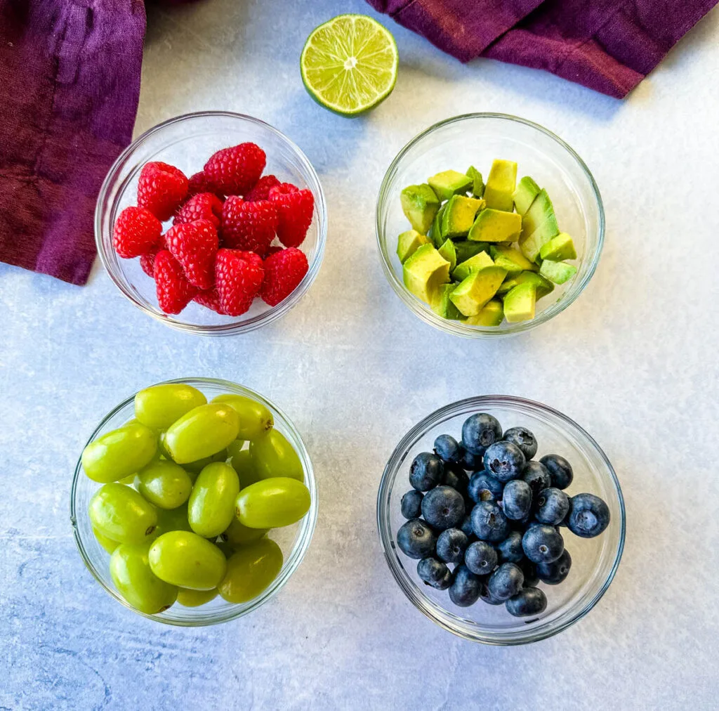 fresh lemon, raspberries, blueberries, grapes, and avocado in separate bowls
