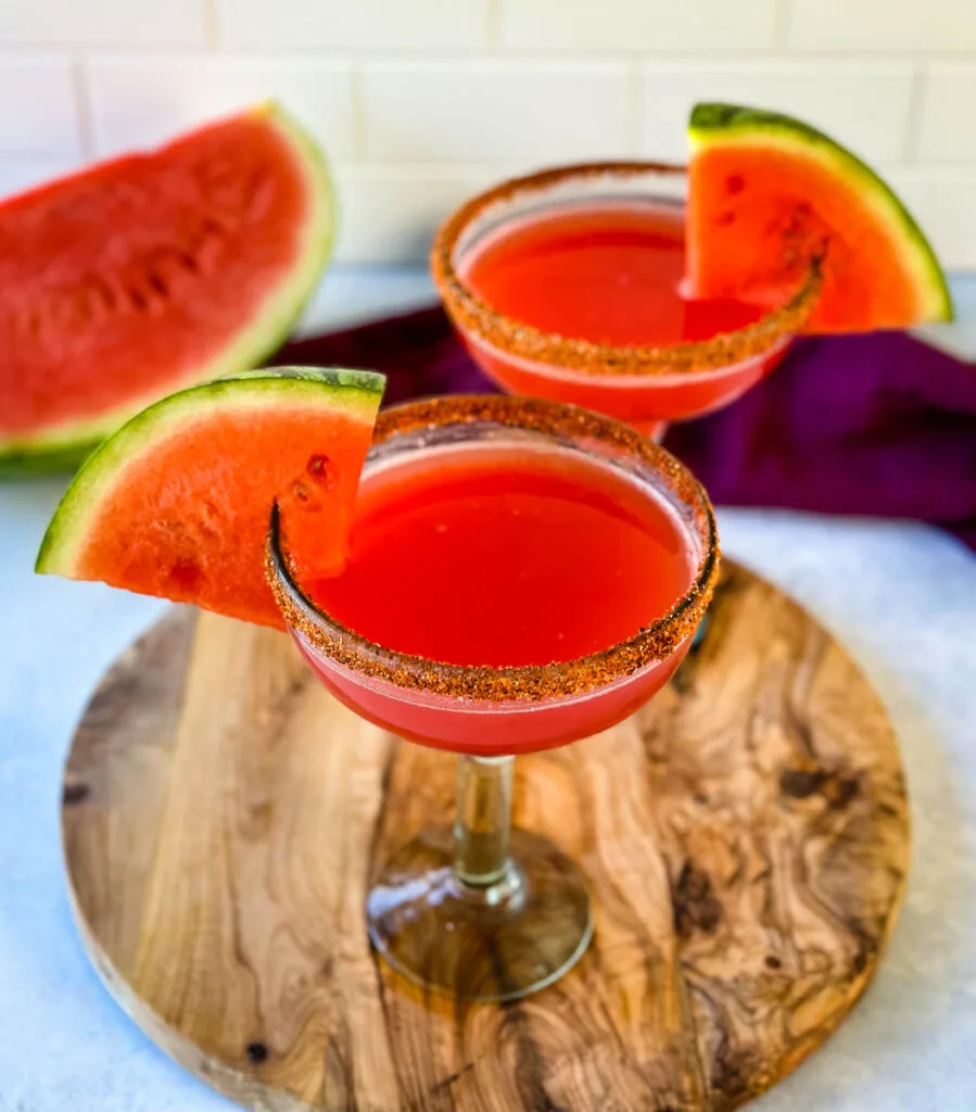 watermelon margaritas on the rocks in a glass with Tajin lined rim and fresh watermelon
