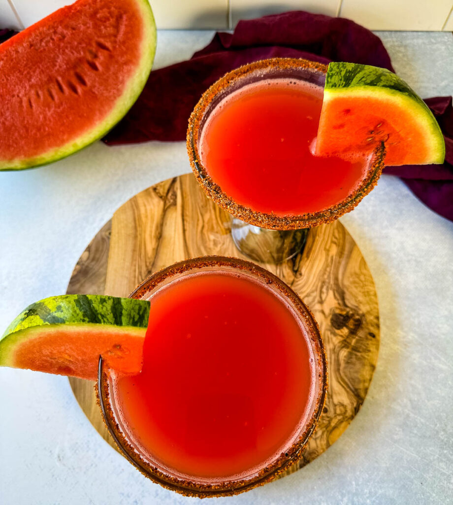 watermelon margaritas on the rocks in a glass with Tajin lined rim and fresh watermelon