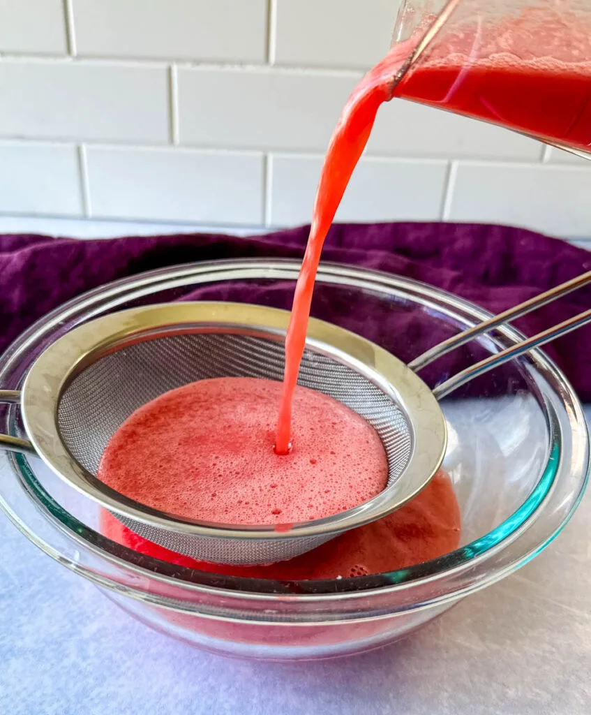 watermelon puree poured into a strainer and glass bowl