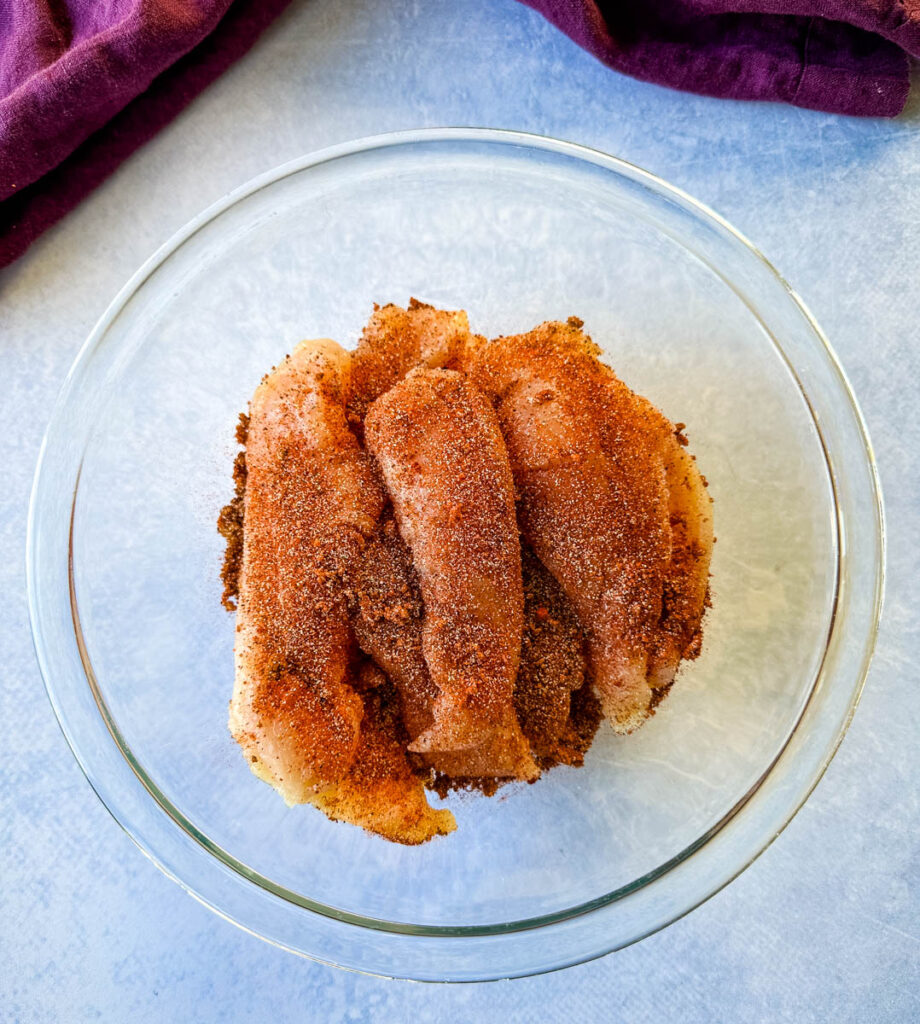 raw seasoned chicken tenders in a glass bowl