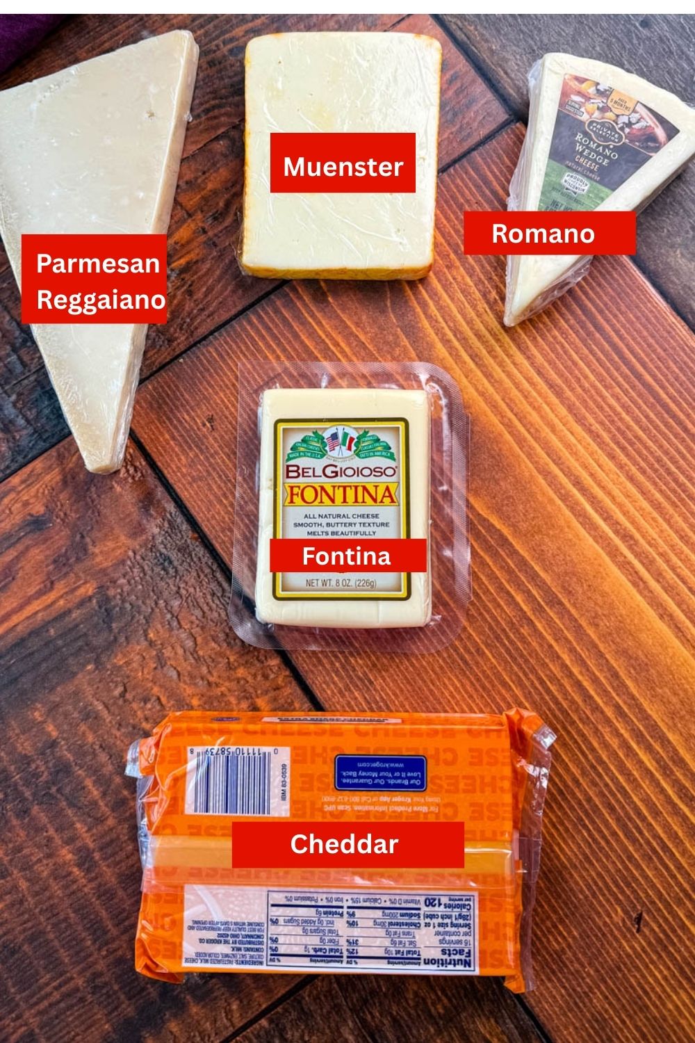 Five different types of cheese displayed on a wooden table: Parmesan wedge, smoked gouda block, Romano wedge, packaged Fontina, and a block of cheddar cheese.