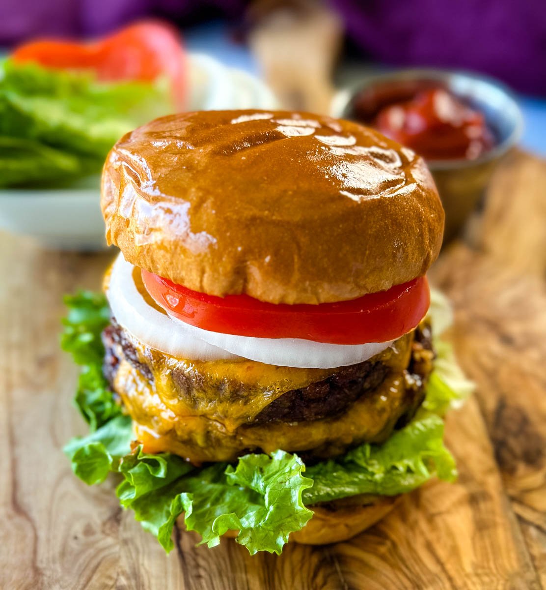 Traeger smoked burger on a bun with cheese, lettuce, tomato, and onions