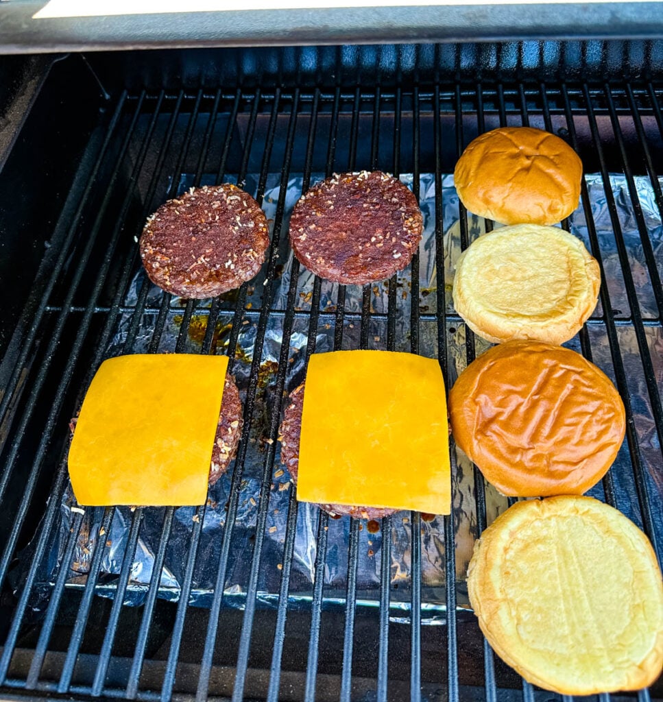 burgers on a Traeger smoker grill with cheese and buns