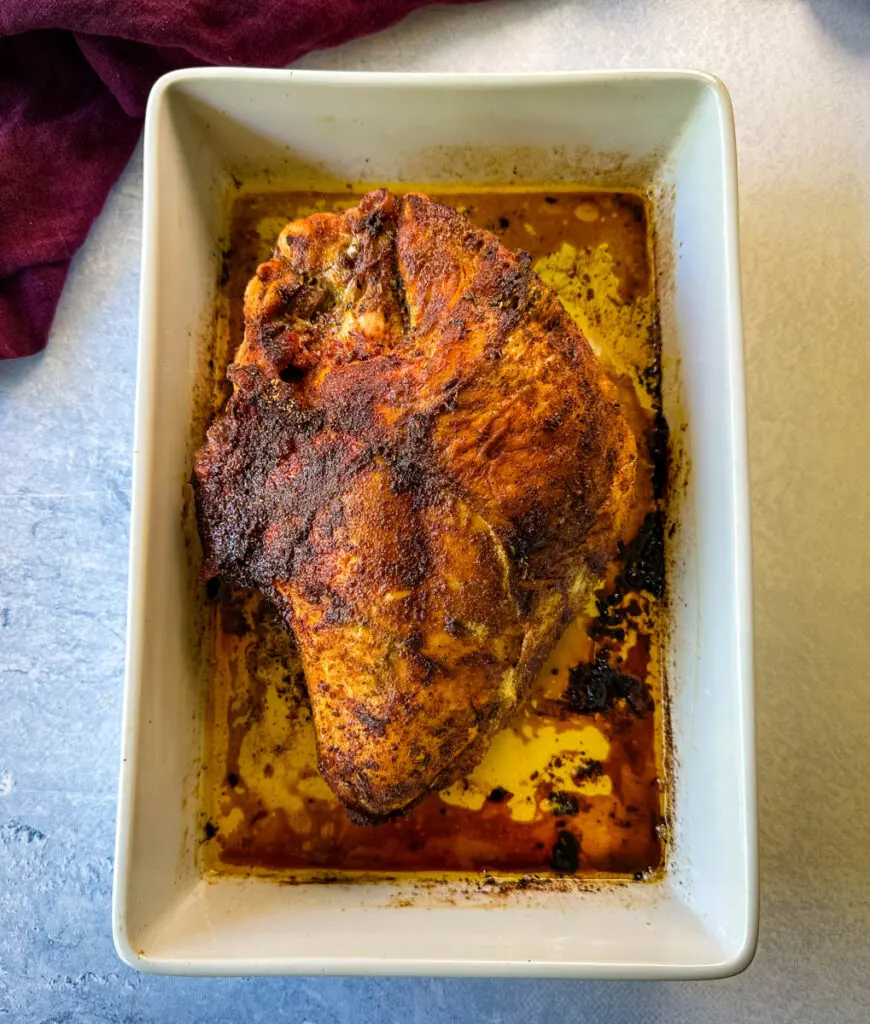 baked roasted bone in turkey breast in a white 9x13 baking dis