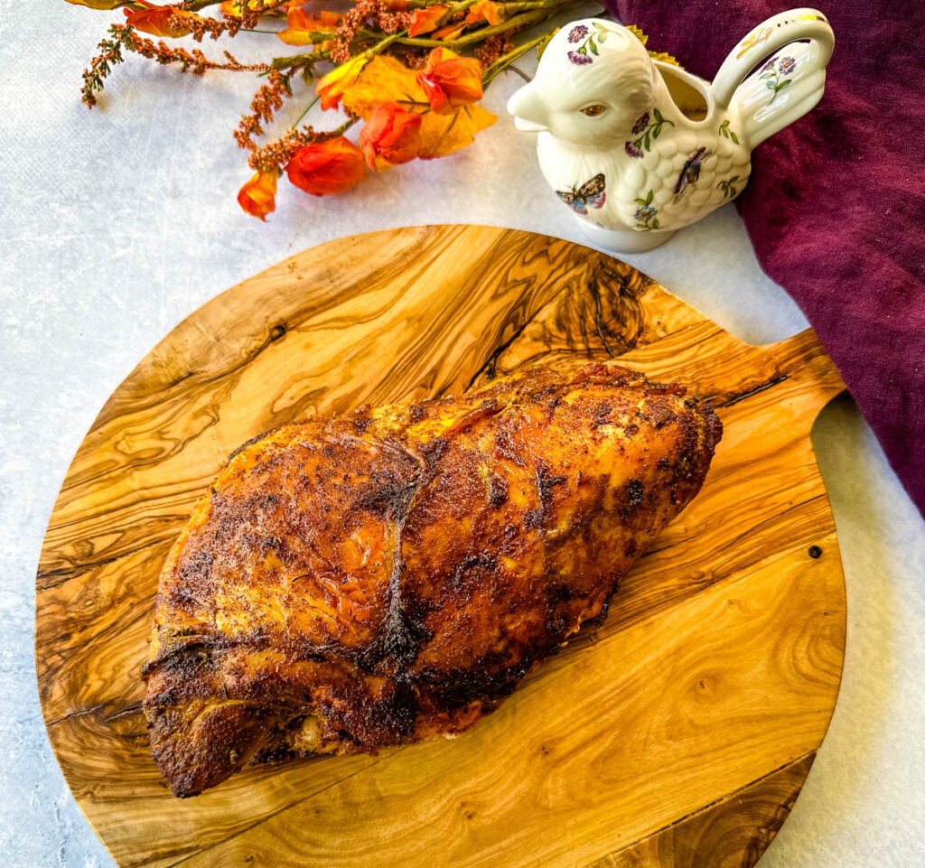 baked roasted bone in turkey breast on a wooden cutting board