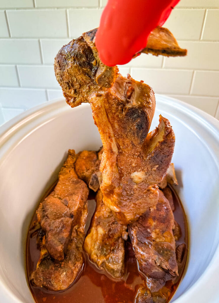 country style ribs falling off the bone of a pair of tongs