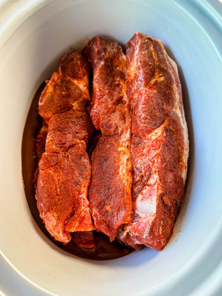 raw country style ribs with BBQ sauce in a slow cooker Crockpot