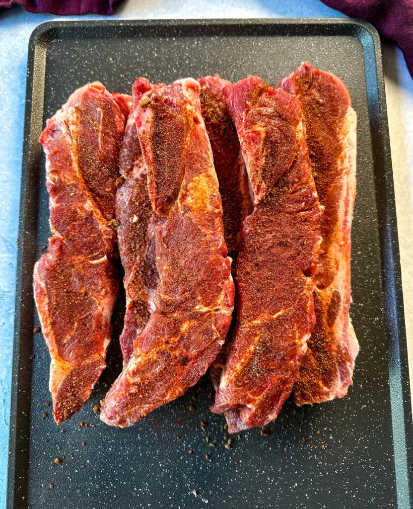 raw, seasoned country style ribs on a sheet pan