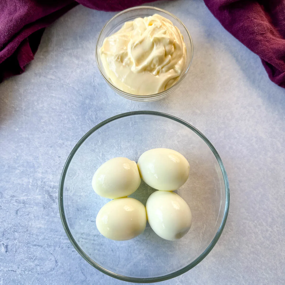 mayo and peeled hard boiled eggs in separate glass bowls