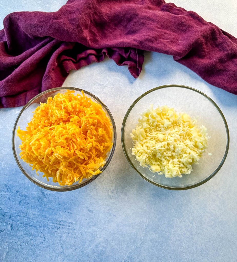 shredded cheddar cheese and mozzarella in separate glass bowls