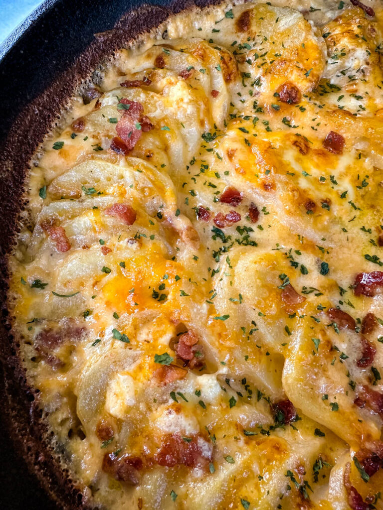 au gratin potatoes with bacon and cheese in a cast iron skillet