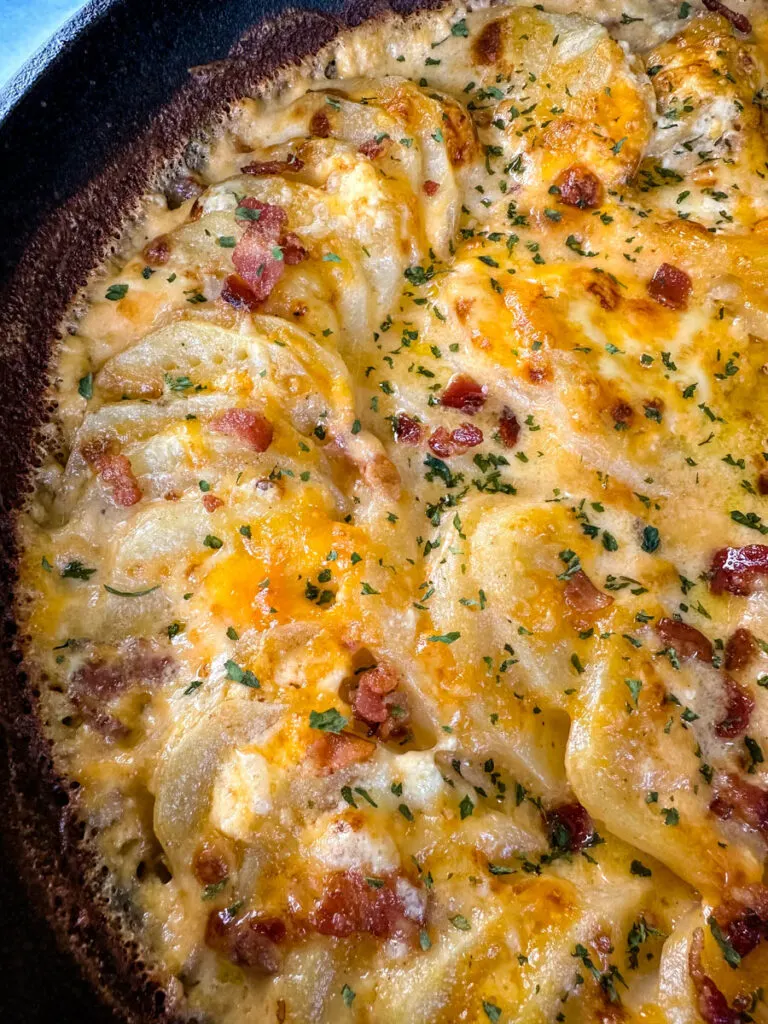 au gratin potatoes with bacon and cheese in a cast iron skillet