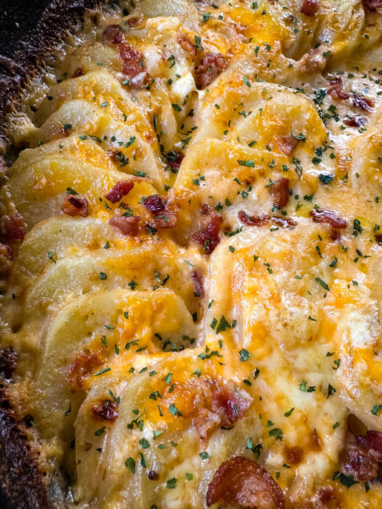 au gratin potatoes with bacon and cheese in a cast iron skillet