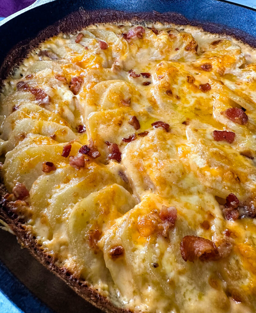 au gratin potatoes with bacon and cheese in a cast iron skillet