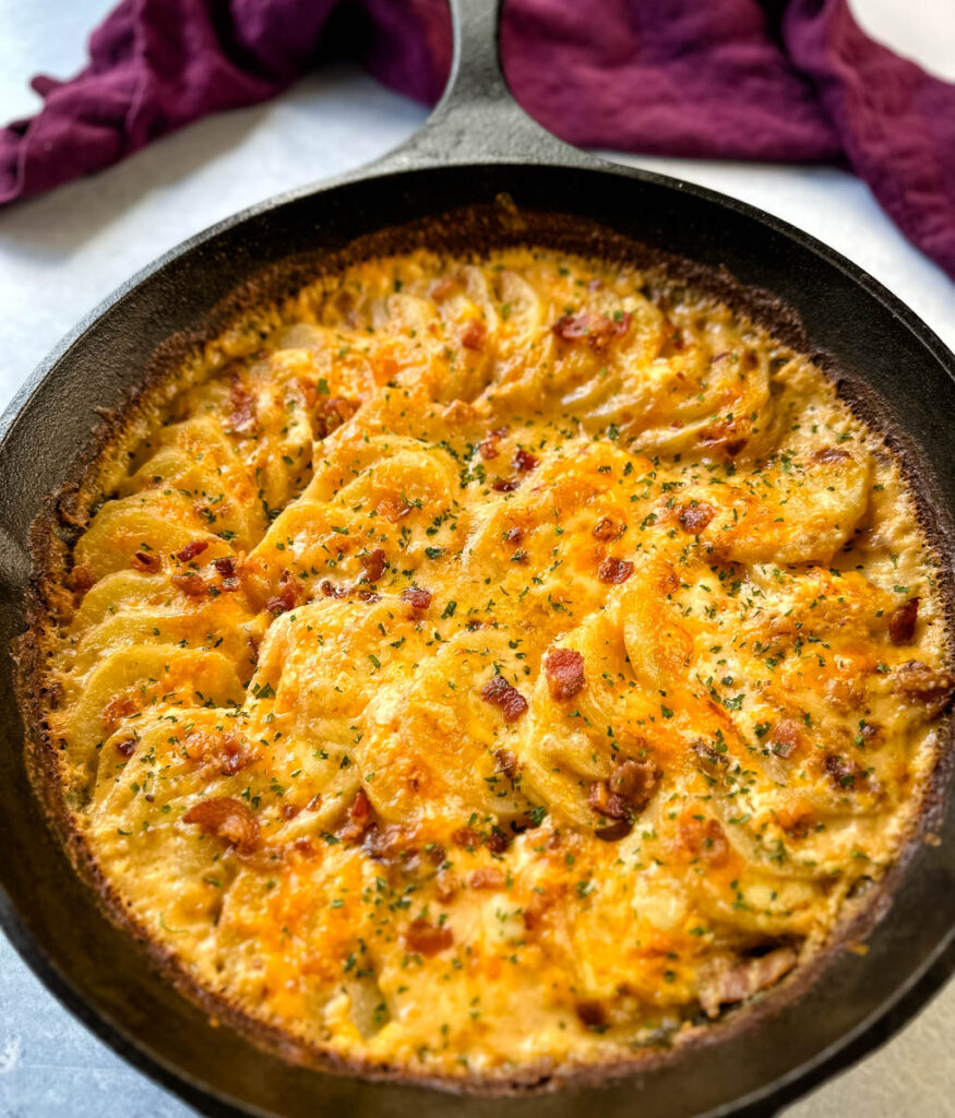 au gratin potatoes with bacon and cheese in a cast iron skillet