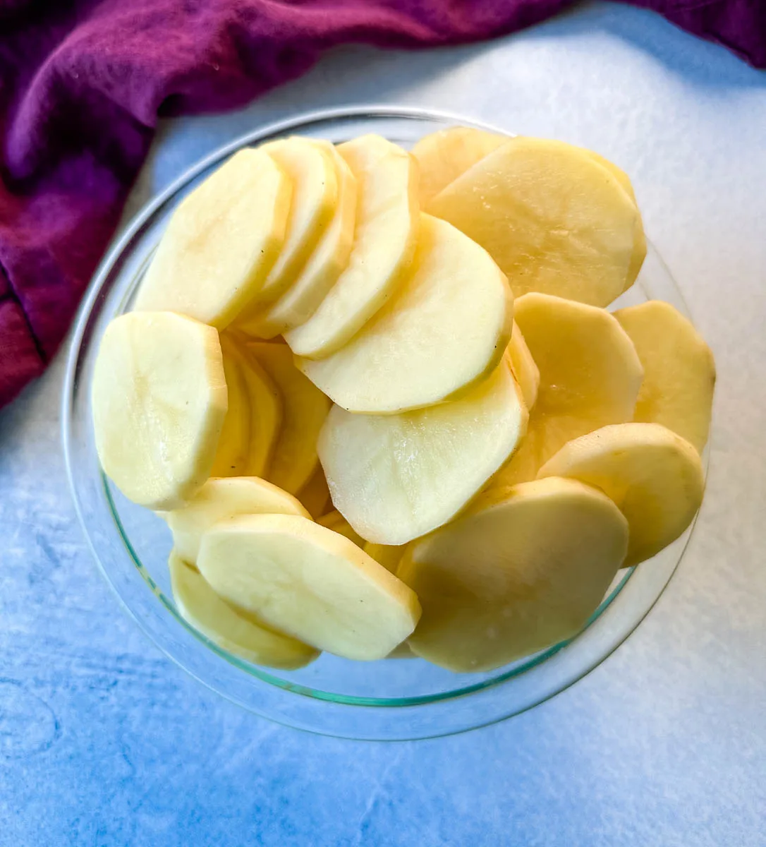 sliced rounds of russet potatoes in a glass bowl