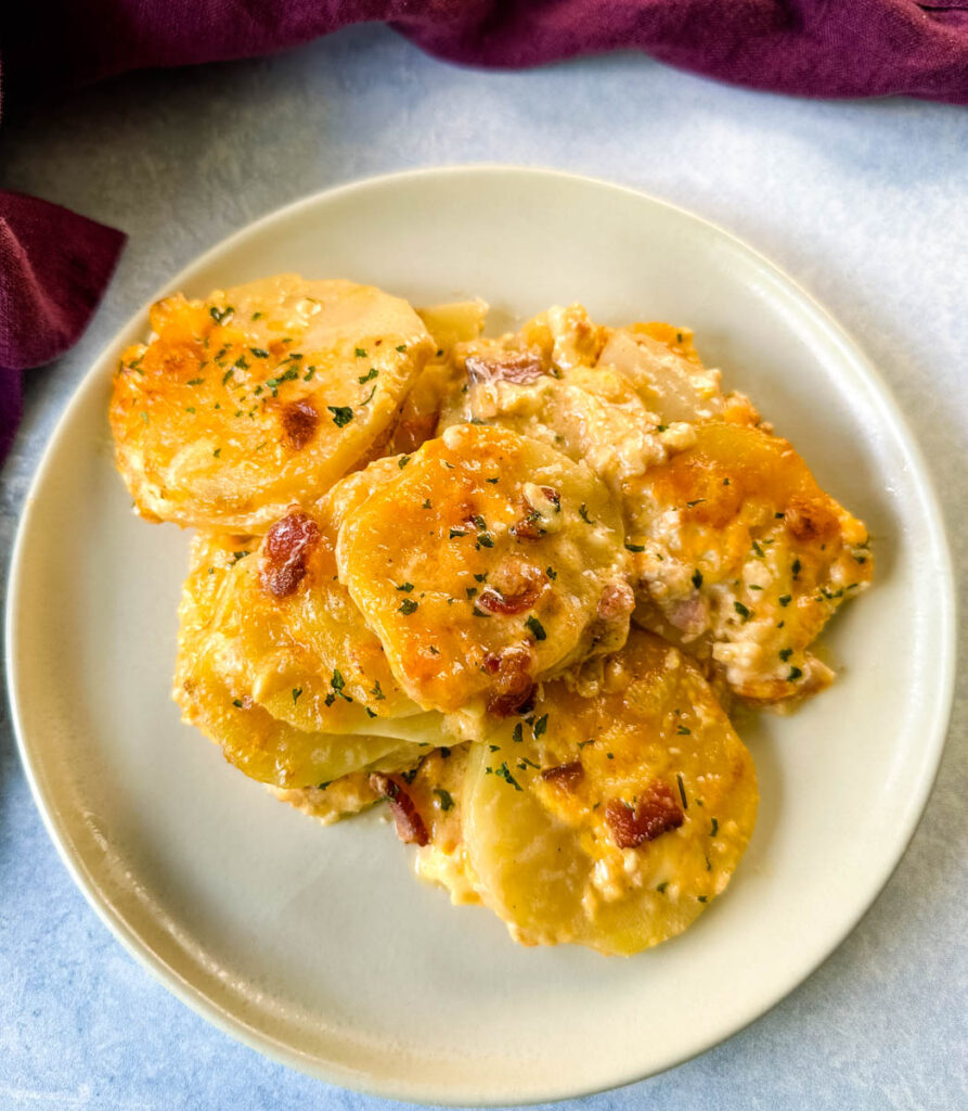 au gratin cheesy potatoes with bacon on a white plate