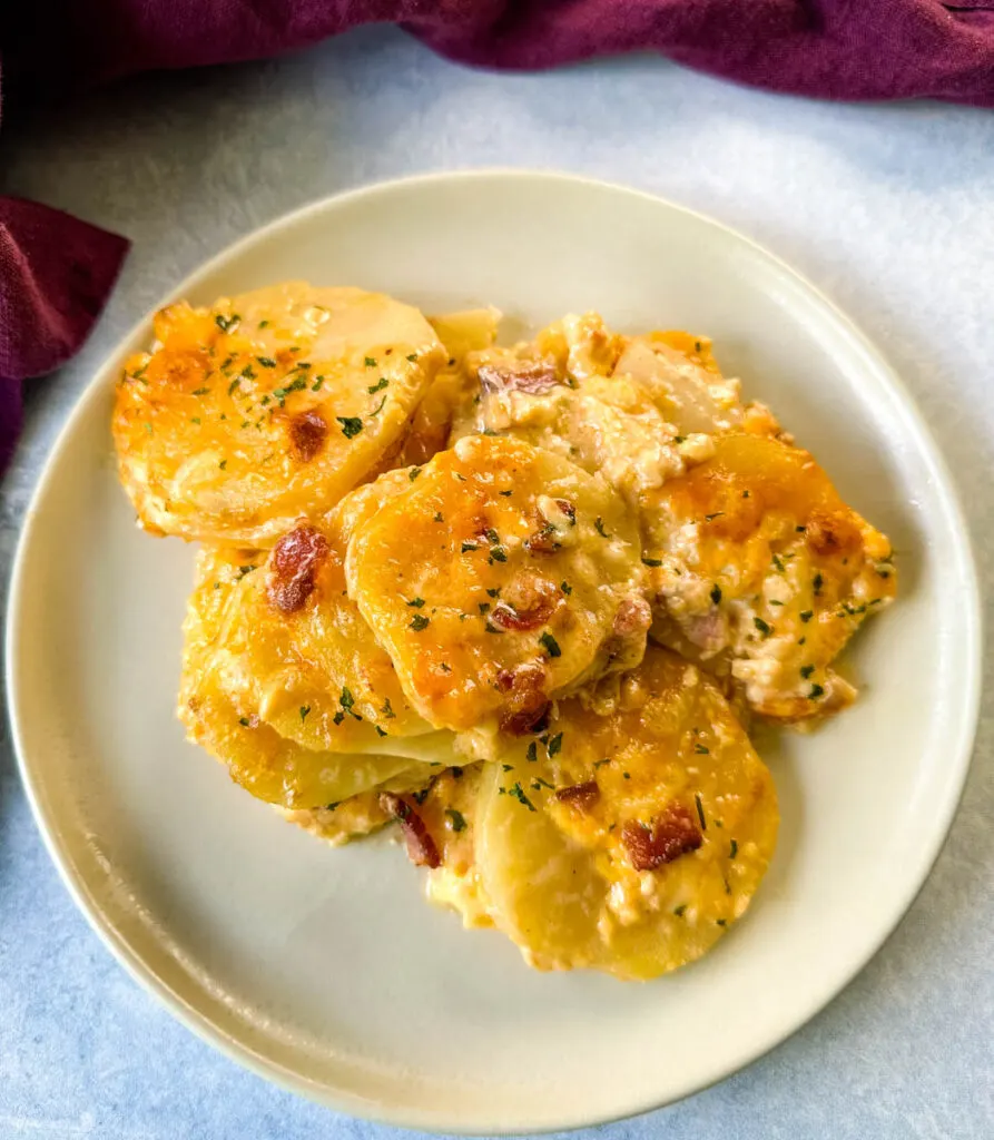 au gratin cheesy potatoes with bacon on a white plate