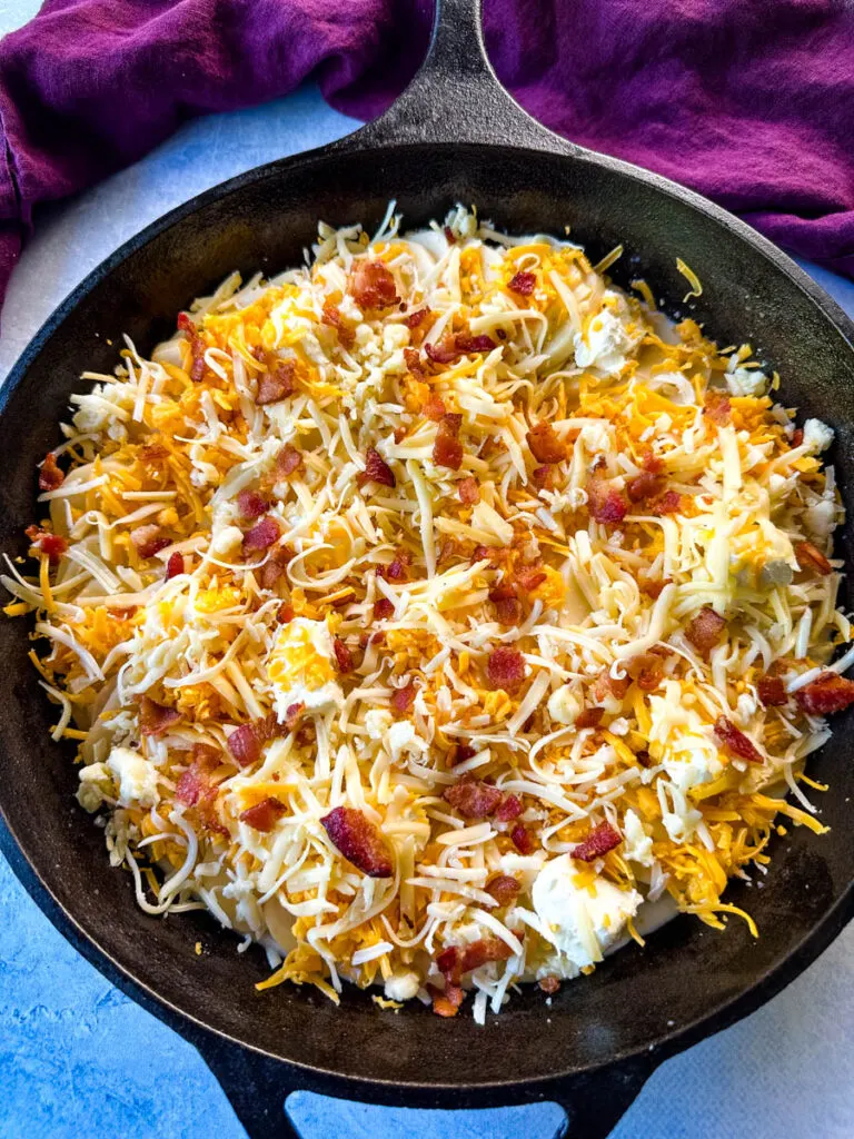 unbaked au gratin potatoes with bacon and cheese in a cast iron skillet