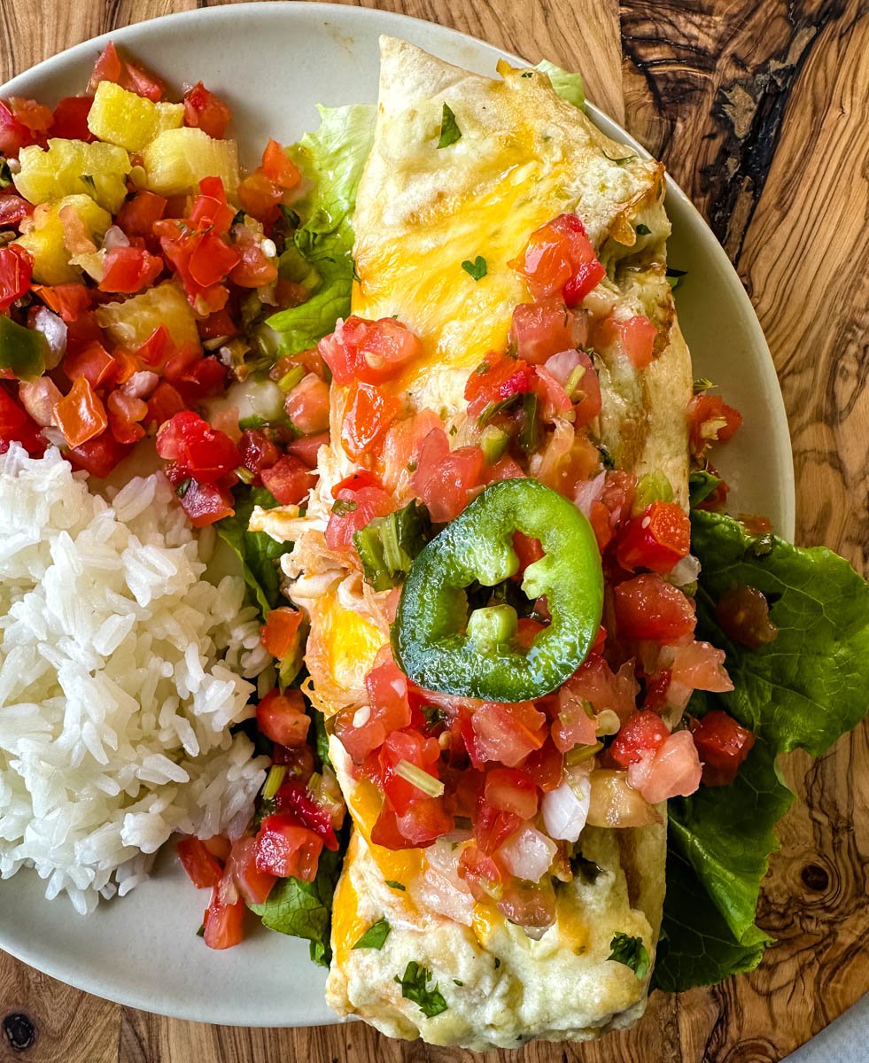 rotisserie chicken enchiladas on a plate with pico de gallo and jalapenos