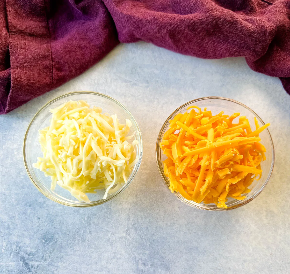 grated cheddar and Monterrey jack cheese in separate glass bowls