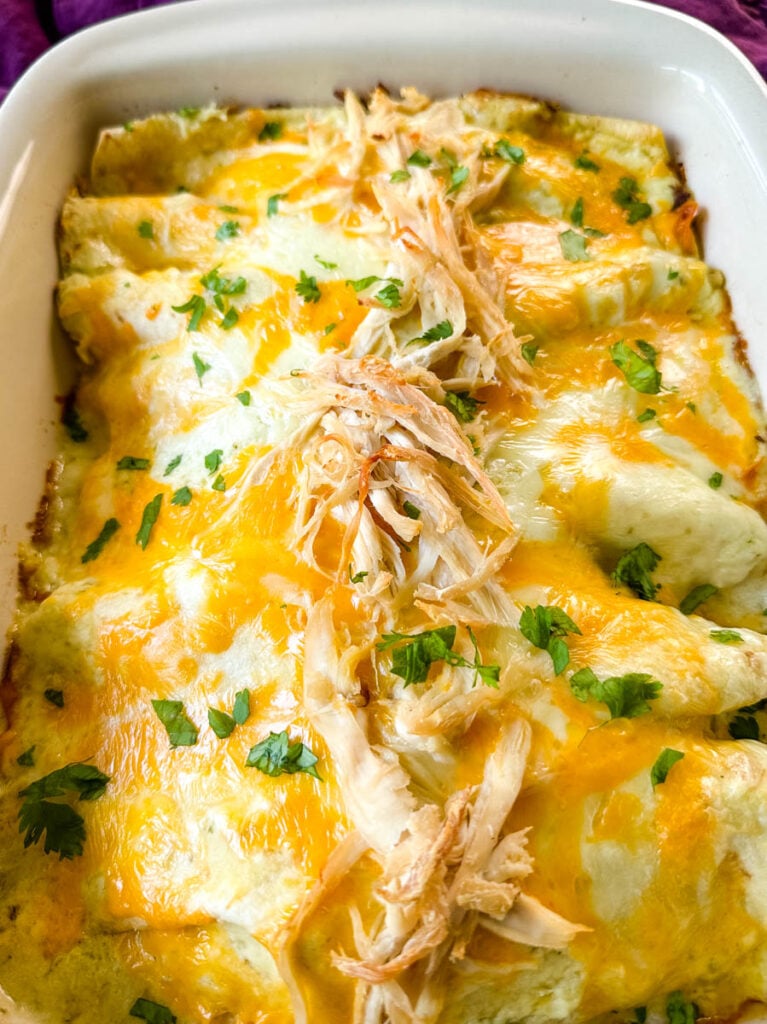 rotisserie chicken enchiladas in a red baking dish