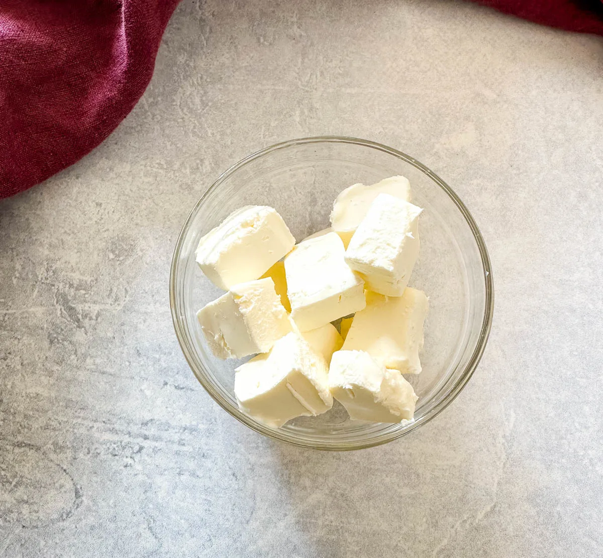 cream cheese cut into chunks in a glass bowl