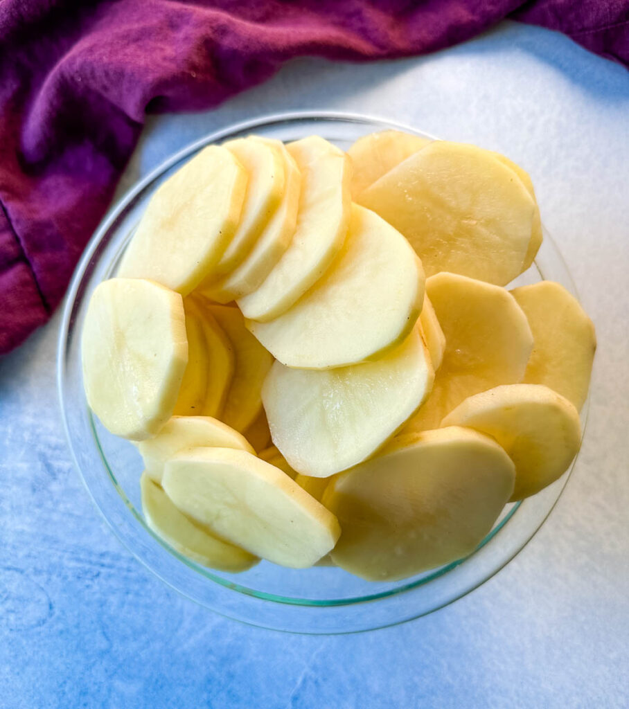 sliced rounds of russet potatoes in a glass bowl