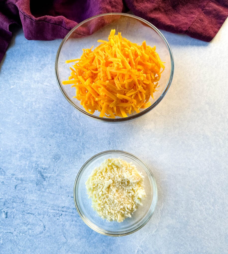 grated cheddar and Parmesan cheese in separate glass bowls