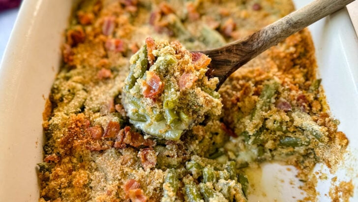 green bean casserole with bacon and breadcrumbs in a baking dish