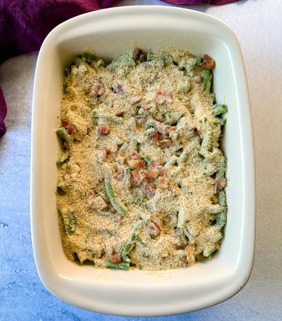 unbaked green bean casserole with breadcrumbs in a baking dish