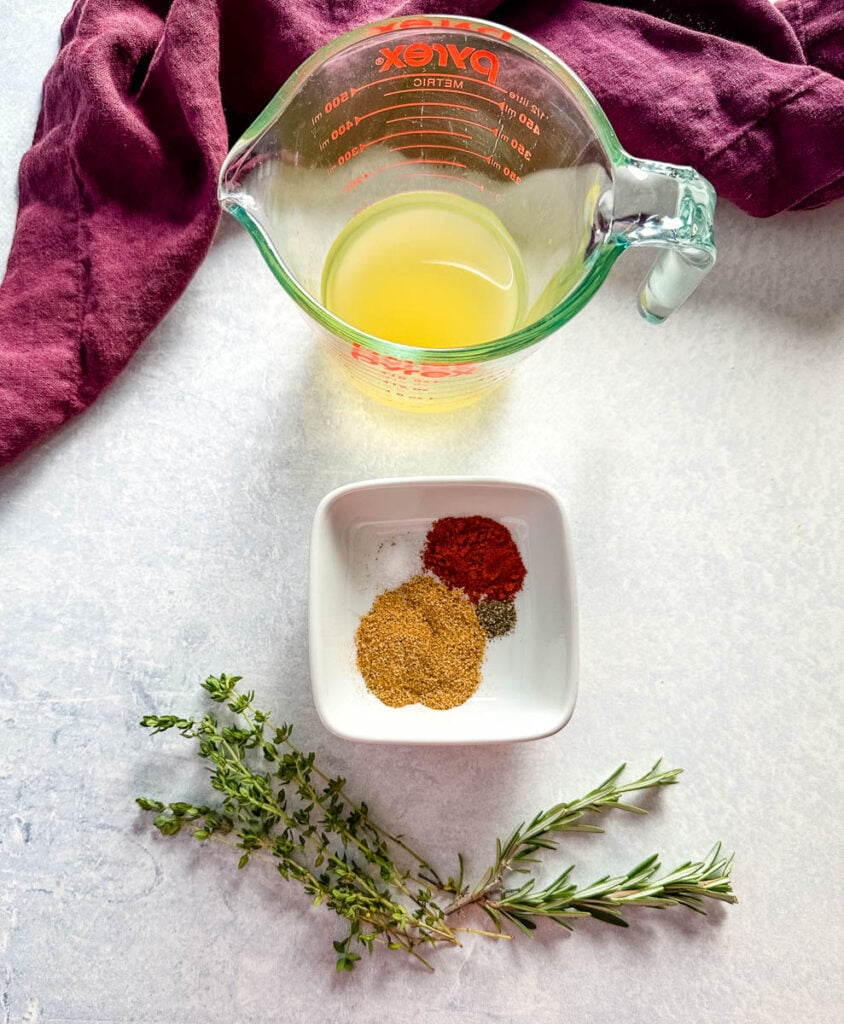 broth in a glass cup and spices in a white bowl