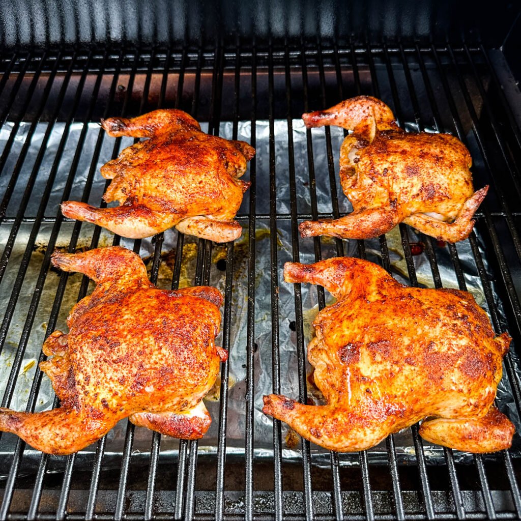 smoked Cornish hens on a sheet pan with fresh herbs