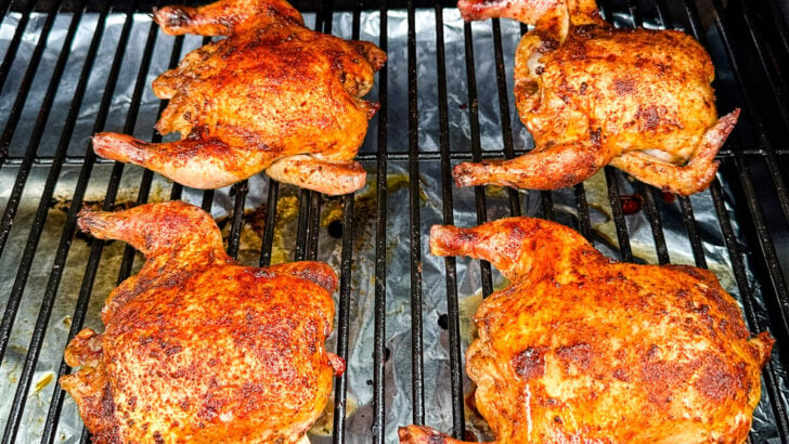 smoked Cornish hens on a sheet pan with fresh herbs