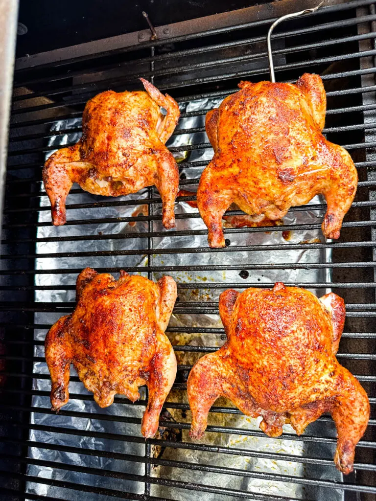 smoked Cornish hens on a sheet pan with fresh herbs